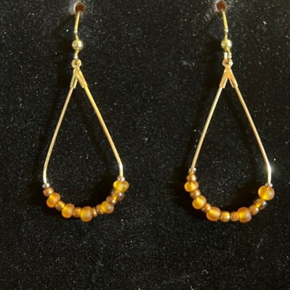 Handcrafted gold tone earrings with brown and beige beading.